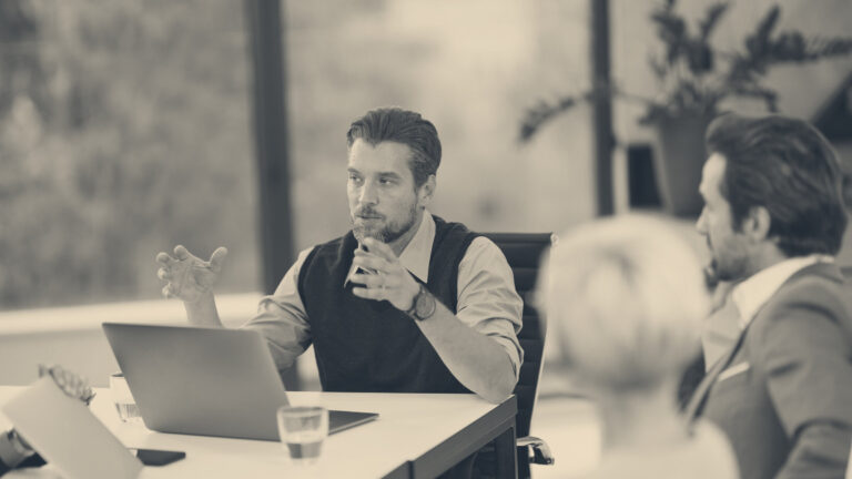 A staff representative speaks to colleagues across a conference table during a workplace consultation meeting.