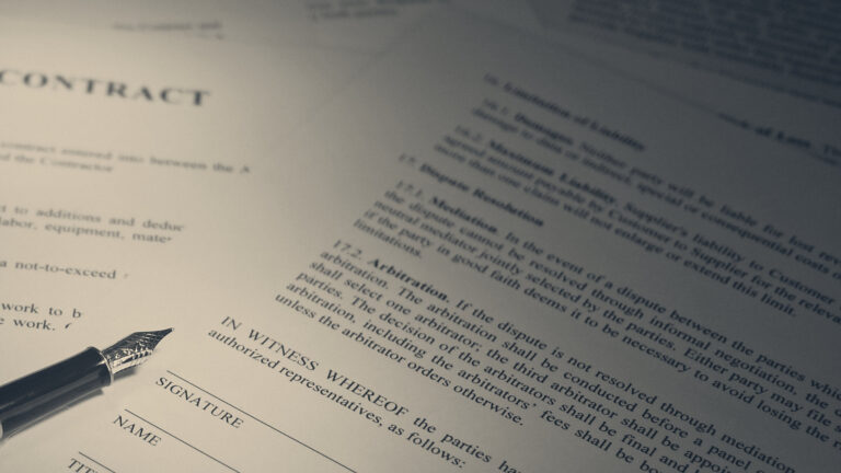 Fountain pen resting on a printed contract page with CONTRACT heading and signature, name and date lines