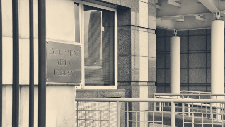 Brass Employment Appeal Tribunal plaque on a grey granite entrance beside a columned walkway ramp
