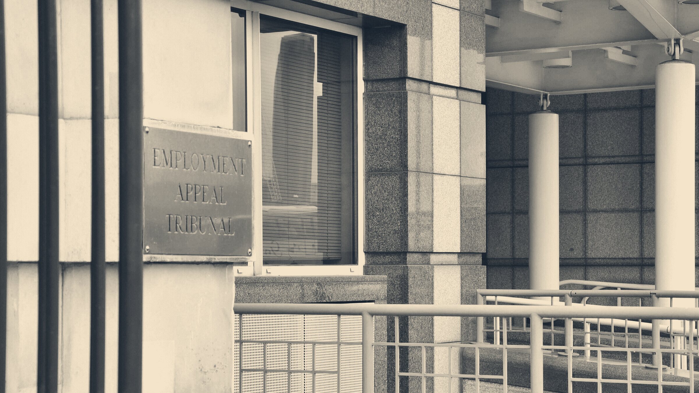 Brass Employment Appeal Tribunal plaque on a grey granite entrance beside a columned walkway ramp