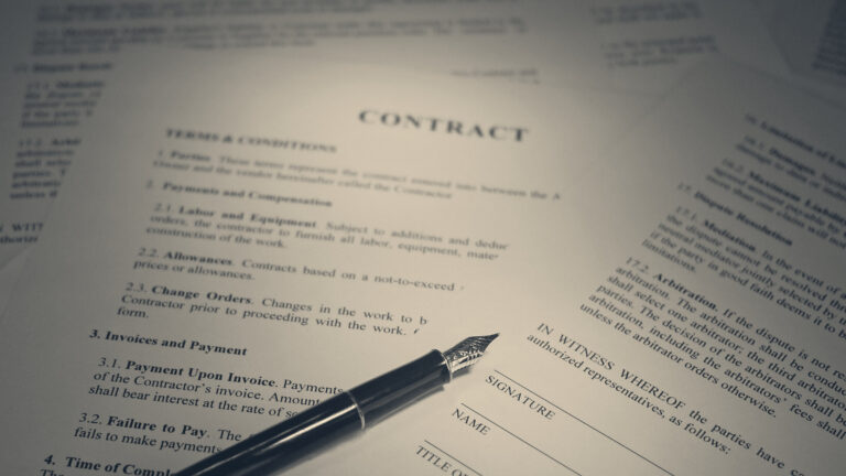 A fountain pen resting on a contract document beside an empty signature line, lit in warm, moody light.