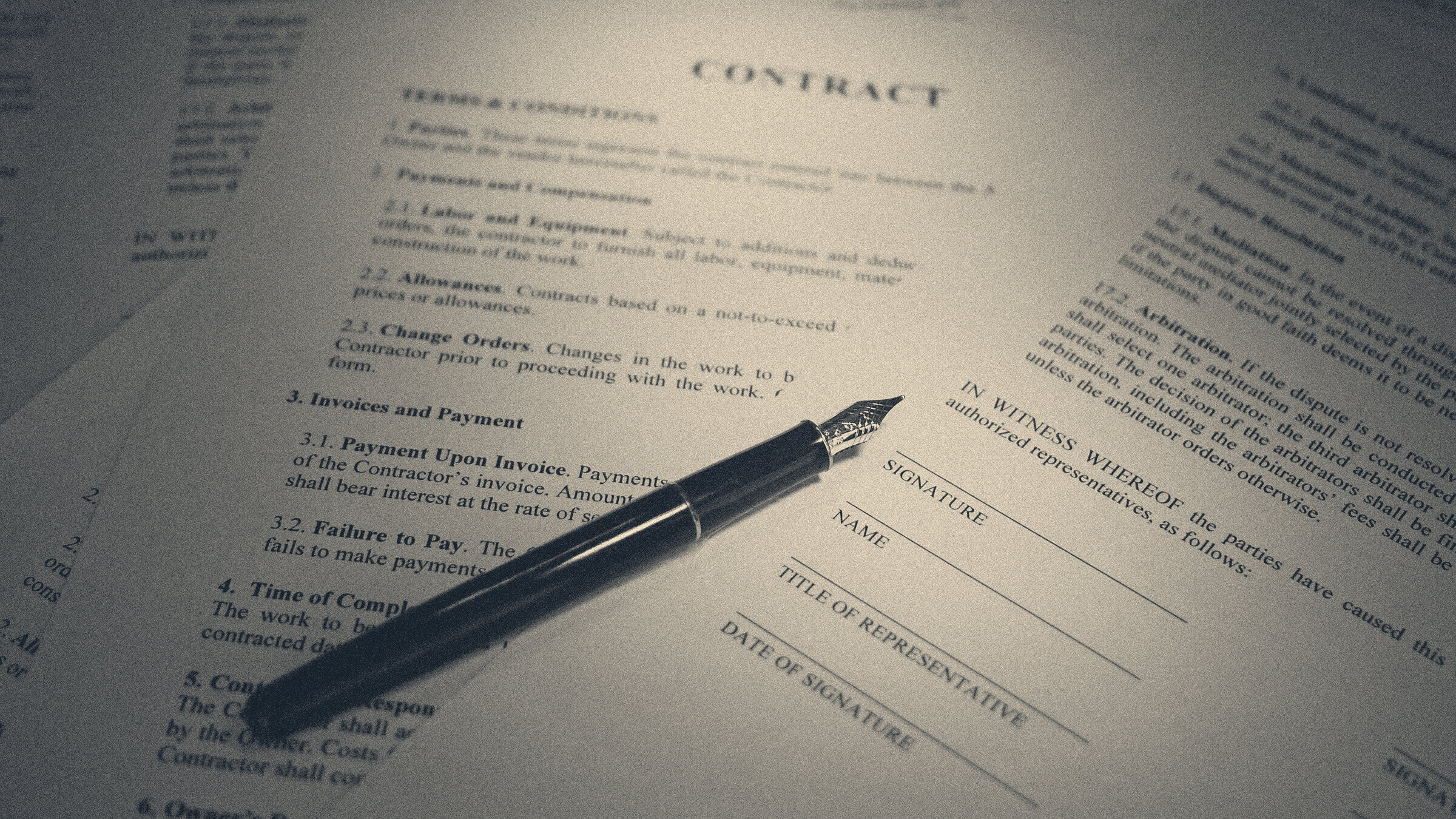 A fountain pen rests on a printed employment contract beside an unsigned signature block under warm light.