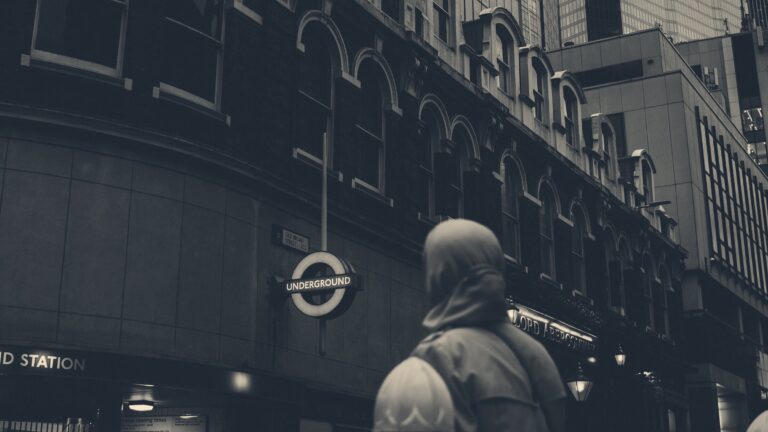 Woman in a teal hijab, seen from behind, on Old Broad Street looking up at City of London office towers