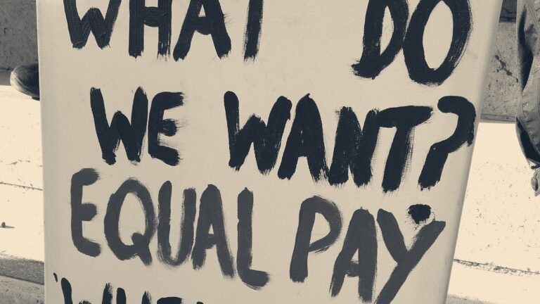 Hand-painted strike placard reading 'What do we want? Equal pay' in black and red letters, 2020 UK university strike.