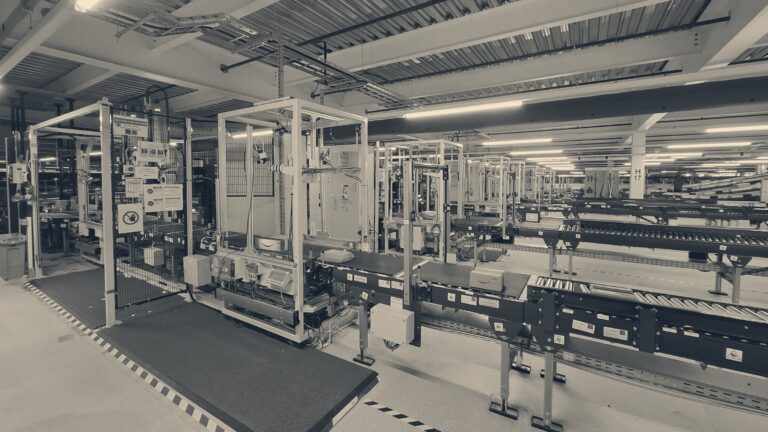 Automated parcel sortation line in a UK fulfilment centre, with caged machinery, red scanning lights and conveyor belts